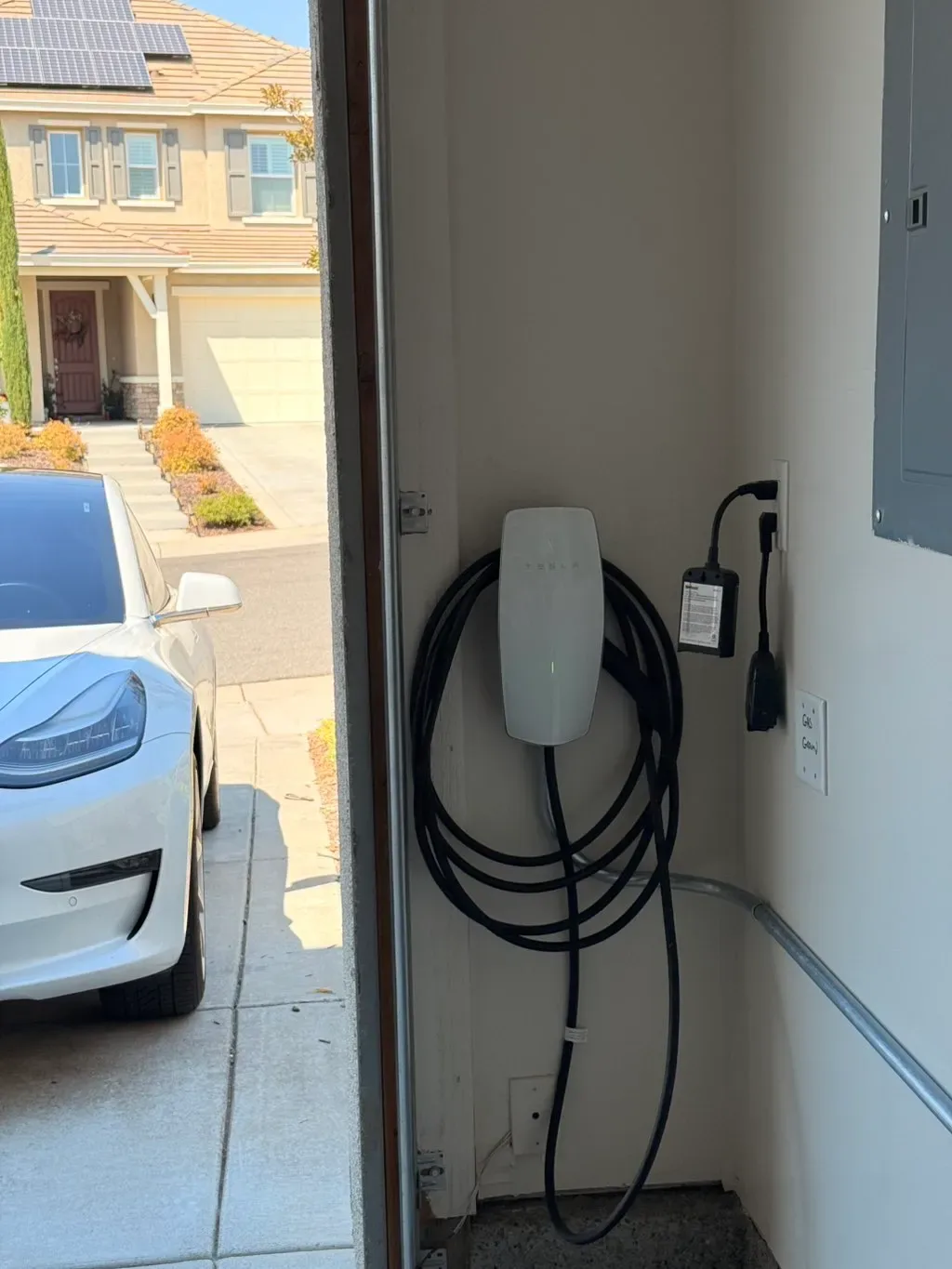 Wall-mounted EV charger beside a residential garage door